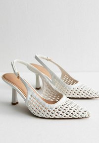 Vita slingback-klackar med ett vävt mönster, spetsiga tår och en blockklack i medelhöjd med en slät läderdetalj.