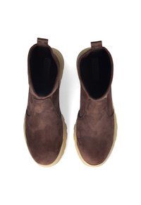 Stivali alla caviglia in suede marrone con punta rotonda, pannelli elasticizzati ai lati e suola in gomma. Presentano un piccolo tab di trazione sul retro per facilitarne l'indossamento.
