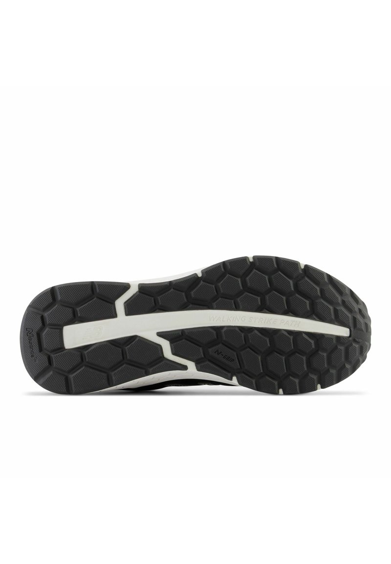 Semelle de chaussure de sport noire avec motif hexagonal, accent de semelle intermédiaire blanche et zones de grip texturées. Comprend la mention "WALKING STRIKE PATH".
