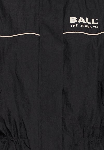 Crna jakna napravljena od laganog materijala. Ima bijele detalje, tekst s logotipom "BALL THE JEANS '74" i elastični struk.