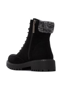 Botín de ante negro con un puño de punto gris texturizado, que cuenta con un zipper lateral y cordones redondos, además de una suela resistente para mayor tracción.