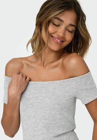 Grå off-shoulder top i et blødt, struktureret stof med korte ærmer og en tætsiddende design, der har et let meleret mønster.