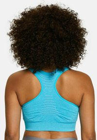 Sujetador deportivo azul con diseño de espalda racer, detalles en paneles texturizados y tejido suave; ideal para comodidad y libertad de movimiento durante los entrenamientos.