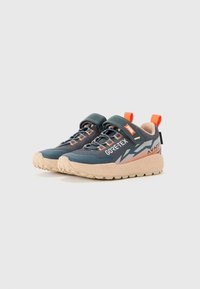Un paio di sneaker Gore-Tex blu e beige con accenti arancioni, fascia in Velcro e suola robusta, esposti su sfondo bianco.