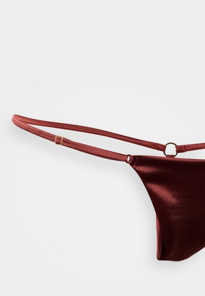 Παντελόνι μπικίνι από βελούδο μπορντό με λεπτές τιράντες και λεπτομέρεια σε χρυσό δαχτυλίδι. Λεία υφή με μίνιμαλ κάλυψη.