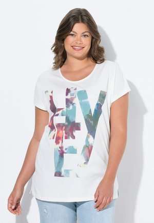 T-shirt blanc à manches courtes arborant un graphique "FLY" multicolore avec un effet aquarelle, coupe décontractée. Associé à un jean bleu clair.