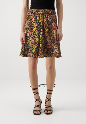 Jupe florale noire avec des fleurs oranges, roses et jaunes. Taille élastique, forme évasée et tissu texturé. Associée à des sandales noires à lanières.