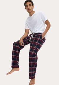 Marineblauwe en bordeaux geruite broek met een trekkoord in de taille, gecombineerd met een simpele witte t-shirt, die een ontspannen pasvorm en een zachte stoftextuur laat zien.