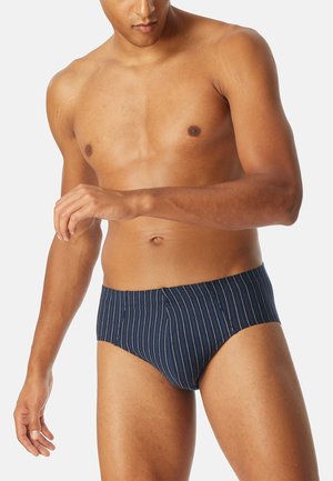 Costume da bagno blu navy realizzato in tessuto liscio, con strisce bianche verticali, cintura elastica e design aderente.