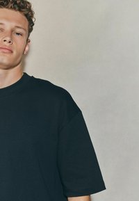 Black cotton t-shirt with short sleeves, relaxed fit, and a crew neckline. Smooth texture and minimal design.