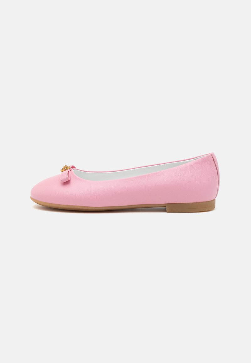 Scarpa piatta rosa realizzata in materiale sintetico con una texture liscia, punta arrotondata e un piccolo fiocco decorativo sulla parte anteriore. Suola bassa e piatta.