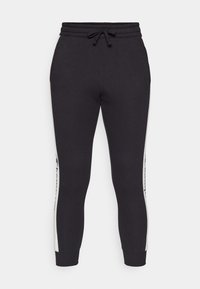 Svart joggebukser med elastisk linning, snor og tapered ben. Side detaljer i lys grå med merke logo. Myk stoff tekstur.