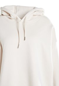 Felpa con cappuccio beige chiaro realizzata in morbido cotone misto. Presenta una tasca a marsupio, lacci con estremità in metallo e polsini a coste.