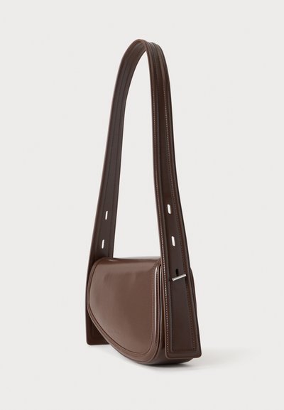 Sac à bandoulière en cuir marron foncé avec une bandoulière extra-large réglable et des détails de coutures minimaux, photographié sur un fond clair uni.