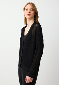 Cardigan nero lavorato a maglia con texture a costine, scollatura a V, chiusura con bottoni e maniche lunghe con dettagli in rete.