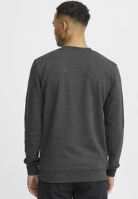 Houtskoolgrijze sweatshirt met lange mouwen, ribgebreide manchetten en zoom. Zachte textuur en eenvoudig ontwerp, met een ontspannen pasvorm.