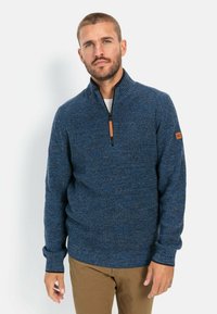 Navy blue zip-up sweater with a textured knit design, featuring a high collar and brown leather accent near the shoulder.