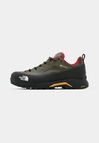 GORE-TEX Wanderschuh in Olivgrün mit schwarzem Gummizeh und Zwischensohle. Verfügt über eine schwarze und gelbe Vibram-Außensohle, pinke Akzente und Schnürsenkel.