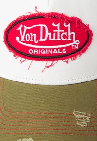 Vit keps med slitna kanter, prydd med en röd och svart broderad Von Dutch Originals-logotyp framtill och en skärm i olivgrön färg.