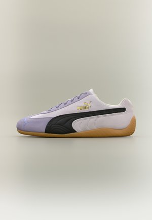 Baskets Puma violet clair et blanches avec une bande noire et une semelle en gomme, vues de côté.