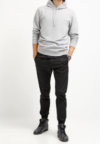 Grå huvtröja med texturmönster, ihop med svarta smalbyxor och svarta högstövlar. Avslappnad passform och neutrala färger.