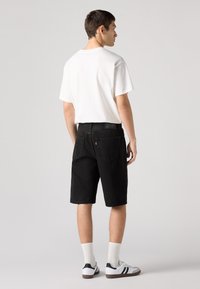 Șorturi din denim negru cu croială dreaptă, asociate cu un tricou alb din bumbac și șosete albe. Încălțările au accente negre și o bază albă.