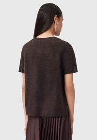 Brązowy sweter z krótkim rękawem, wykonany z miękkiej, teksturowanej tkaniny, o luźnym kroju i okrągłym dekolcie, zestawiony ze spódnicą plisowaną.