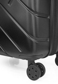 Maleta rígida negra con rayas texturizadas horizontales, cierre resistente y cuatro ruedas negras para mayor movilidad.