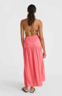 Jupe maxi corail avec une texture fluide et douce. Design fluide avec une taille élastique, associé à un haut de bikini à motifs.