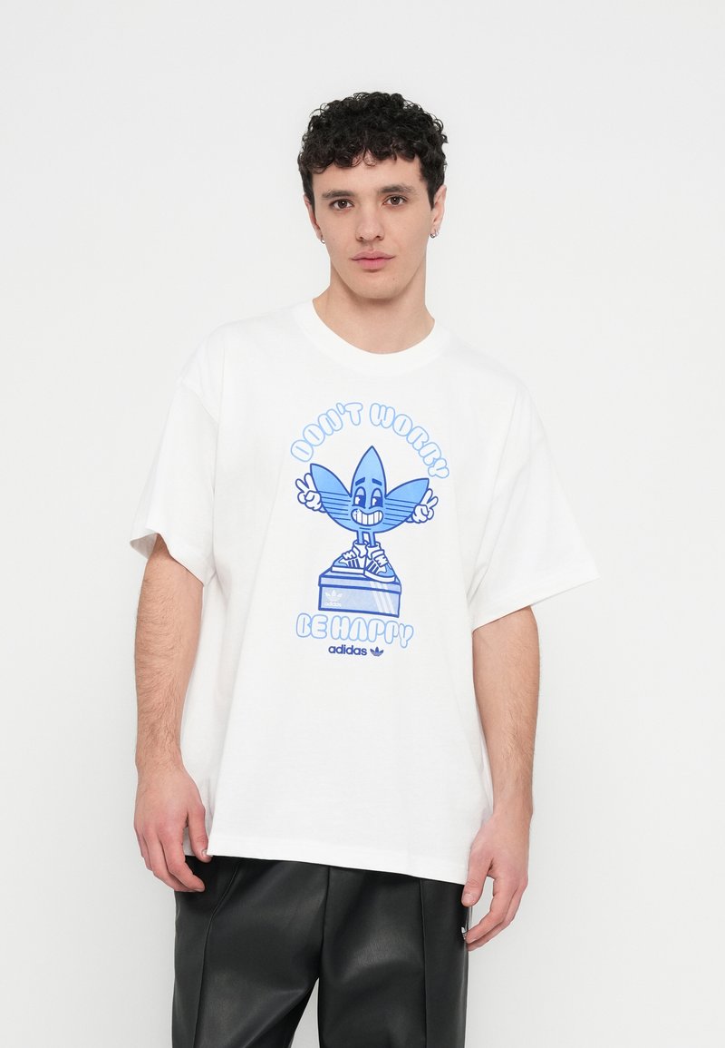 T-shirt branca de algodão com uma imagem gráfica azul de um personagem de desenho animado sorridente, com o texto "Don't Worry Be Happy" e o logotipo da Adidas.