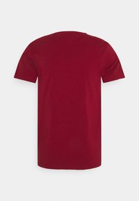 Rød bomulds T-shirt med korte ærmer, klassisk rund halsudskæring og ensfarvet ryg. Ingen synlige logoer eller dekorationer.