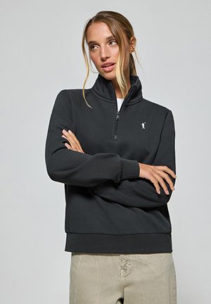 Sudadera negra de cuello alto con media cremallera y logo blanco, que cuenta con mangas largas y puños acanalados, confeccionada en una suave tela texturizada.