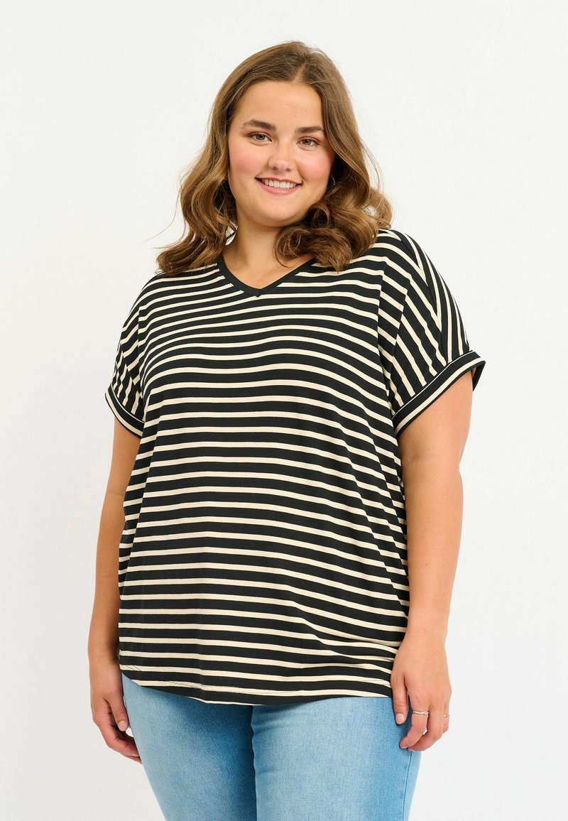 Top de manga corta a rayas en negro y crema, con escote en V y mangas enrolladas, combinado con jeans de mezclilla azul claro. Ajuste suave y relajado, diseño simple.