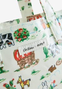 Hvid stofpose med et farverigt mønster af dyr, vogne og planter. Inkluderer et mærke med "Cath Kidston × mitty." Tekstureret overflade.