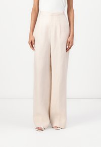 Pantalones de lino anchos color beige con cintura alta, que presentan una textura suave y un diseño limpio y minimalista. Sin bolsillos visibles ni adornos.