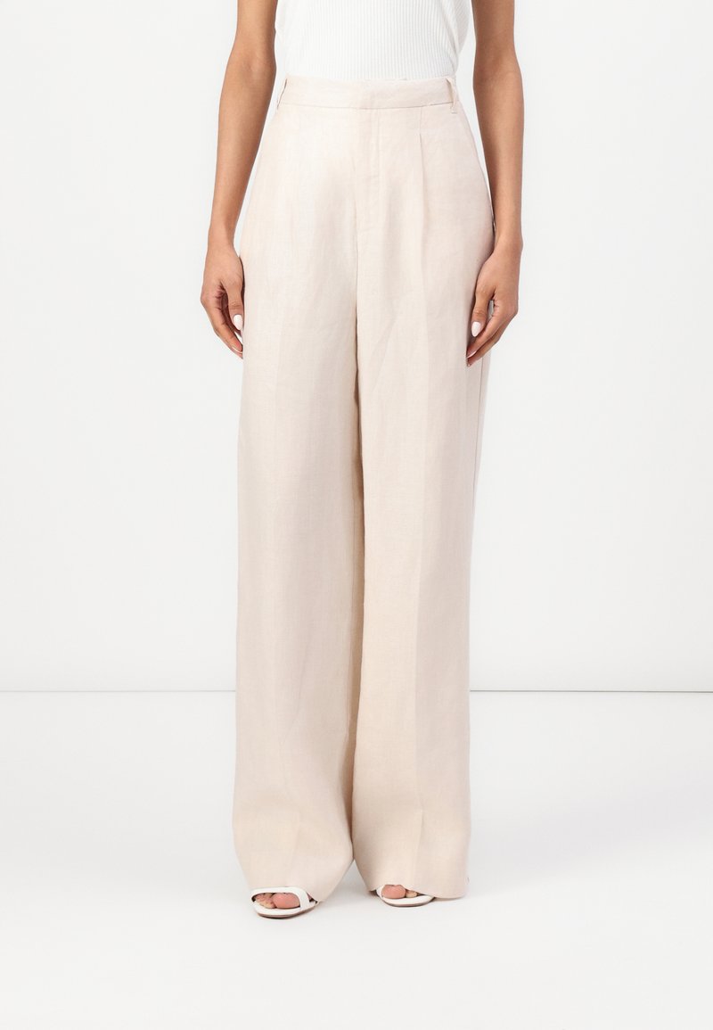 Pantalones de lino anchos color beige con cintura alta, que presentan una textura suave y un diseño limpio y minimalista. Sin bolsillos visibles ni adornos.