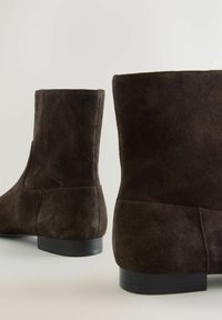 Bruine suède enkellaarsjes met een gladde textuur, een ronde neus en een lage zwarte rubberen hak, met een eenvoudig ontwerp en zonder zichtbare sluitingen.