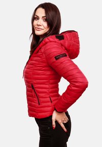 Red padded jacket with a zippered front, black accents, and a hood. Features include two side pockets and a logo patch on the sleeve.