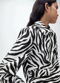 Zebraprint jas in zwart en wit, met een dubbelzijdige sluiting, een geknipt kraag en zijzakken van een gestructureerde stof.