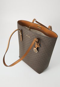 Sac fourre-tout en toile monogram marron avec des poignées en cuir tan, quincaillerie dorée et une poche zippée à l'intérieur. Comprend un charm logo attaché.