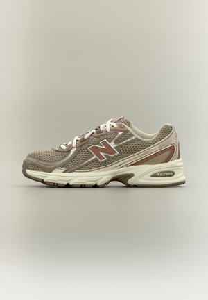 Lysebrun og beige New Balance 740 løbesko med hvide snørebånd og mesh-detaljer, vist fra siden på en neutral baggrund.