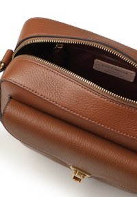 Borsa a tracolla in pelle marrone con dettagli in oro, chiusura con cerniera e superficie morbida e strutturata, con etichetta in pelle all'interno.