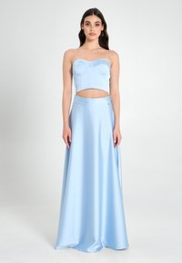 Zweiteiliges Outfit bestehend aus einem trägerlosen, hellblauen Crop-Top mit Brustnähten und einem hochgeschnittenen, fließenden Maxirock in der gleichen Farbe.