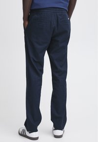 Tumši zili brīvā stila bikses ar saites vidukli, divām aizmugures kabatām un apaviem. Mīksts, viegls audums.