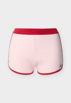Pantaloni scurți sport de culoare roz deschis, cu talie și margini roșu închis, având un mic logo Adidas roșu închis în partea dreaptă jos a piciorului.