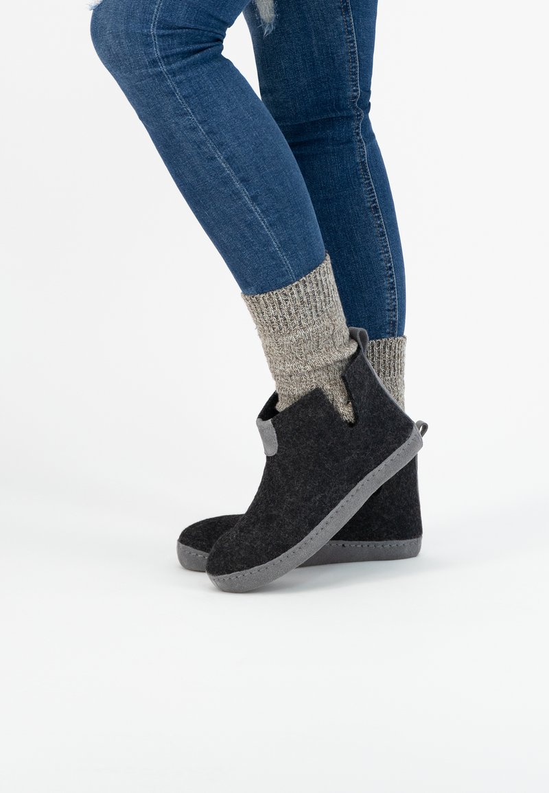 Grijze enkellaarsjes met verstevigde grijze zolen, voorzien van een trekhaak en ribbelige beige gebreide sokken, gecombineerd met donkerblauwe jeans.