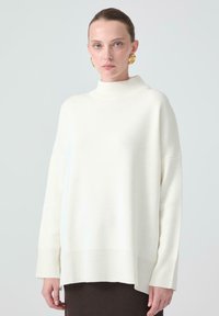 Hvid, oversized turtleneck trøje i et blødt strikstof med ribbede manchetter og kant, der har en afslappet pasform og dropped shoulder-design.