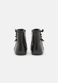 Black ankle boots made of smooth leather, featuring a rounded toe, back laces, and a low, flat sole with contrasting stitching.