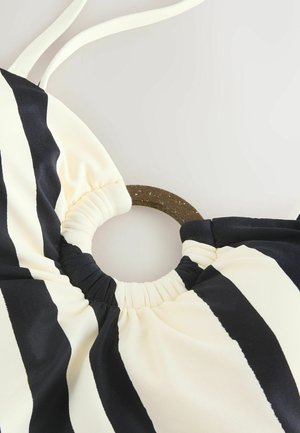 Top bikini a strisce nere e crema con un accentuazione circolare marrone, caratterizzato da tessuto arricciato sul colletto e spalline regolabili.