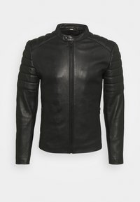 Veste en cuir noire avec épaules matelassées, fermeture éclair à l'avant et col à boutons pression, présentée sur un fond clair uni.